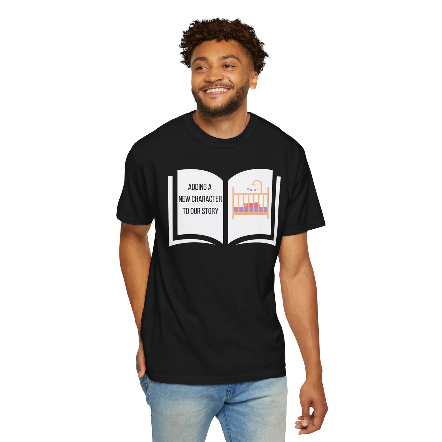 Black t-shirt featuring an open book graphic with the text "Adding a New Character to Our Story" and an image of a crib/baby booties/teddy bear, symbolizing a pregnancy announcement.