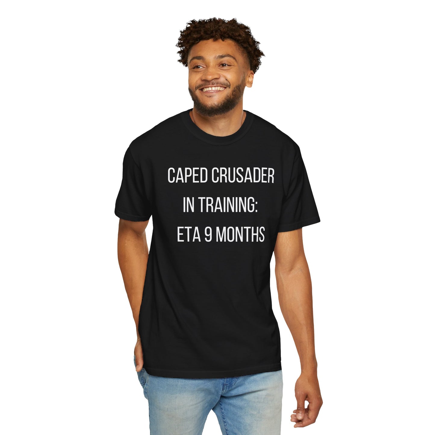 Black t-shirt with the text "Caped Crusader in Training: ETA 9 Months" in a playful superhero-themed font.