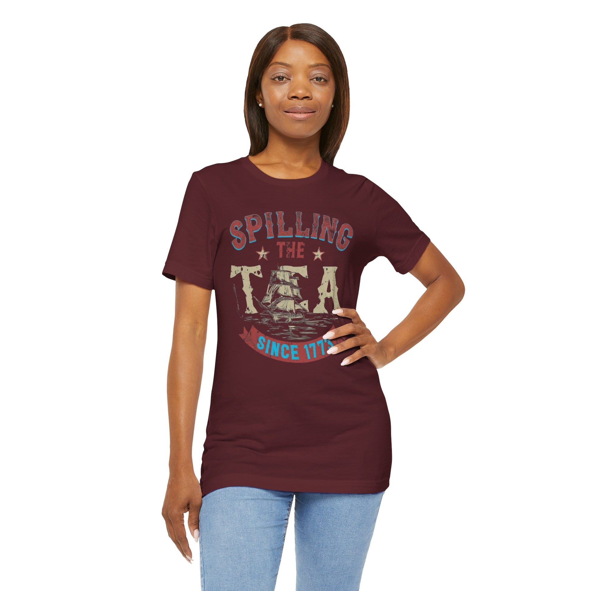 Various t-shirts featuring the text "Spilling the Tea Since 1773" with vintage-inspired graphics of ships and patriotic elements.