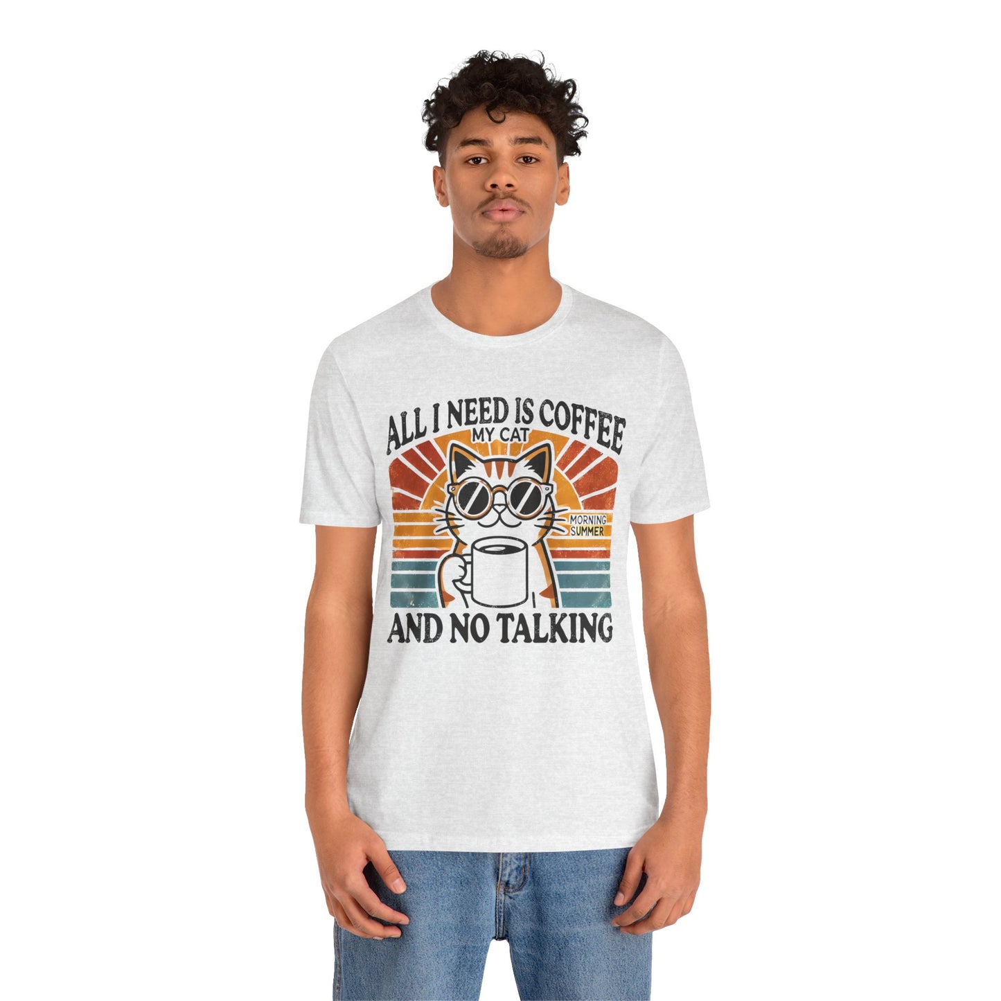 A light-colored t-shirt with a retro design of a cat wearing sunglasses, holding a coffee cup, and the text "All I Need is Coffee and My Cat.