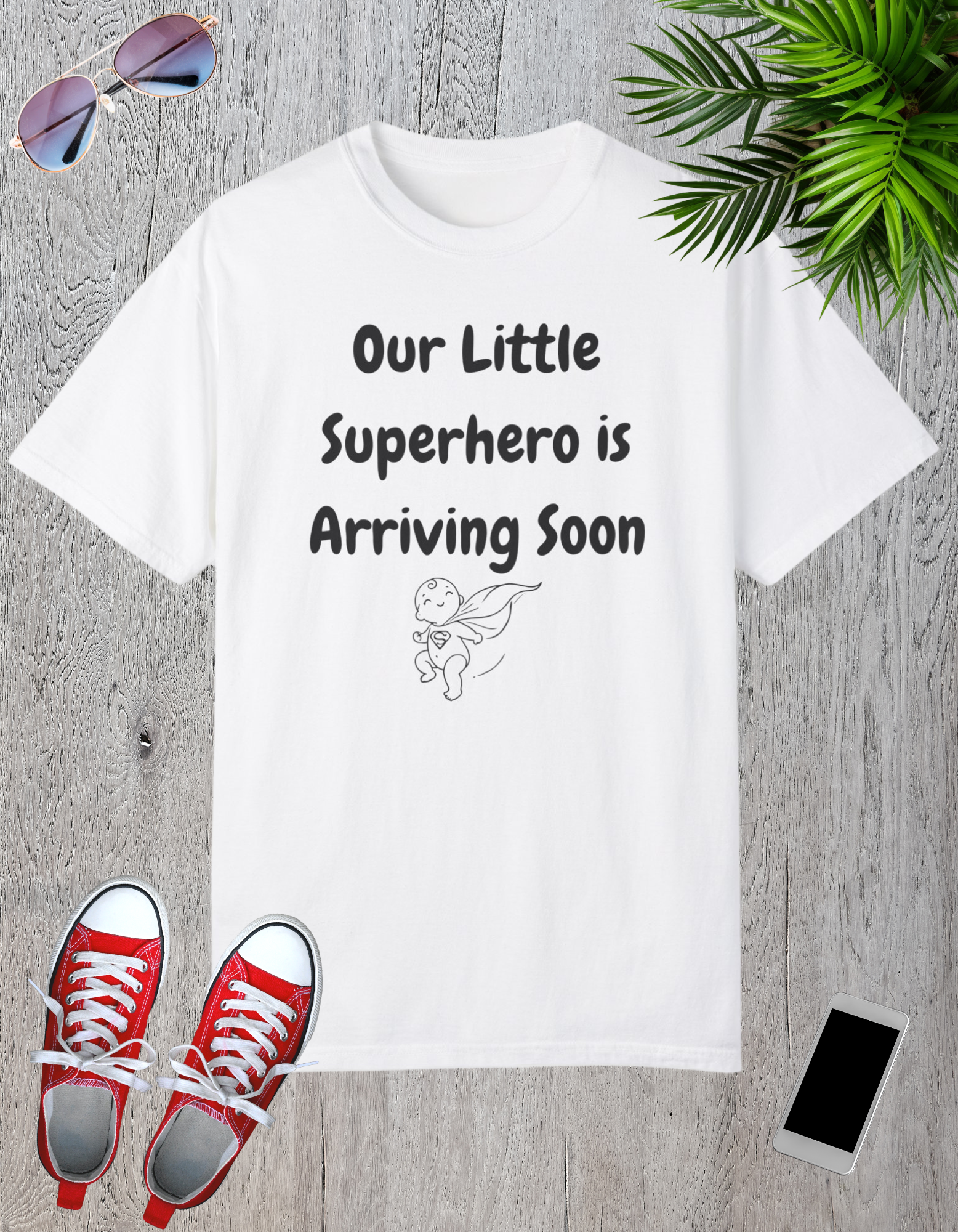 White t-shirt featuring the text "Our Little Superhero is Arriving Soon" with a cute superhero graphic.