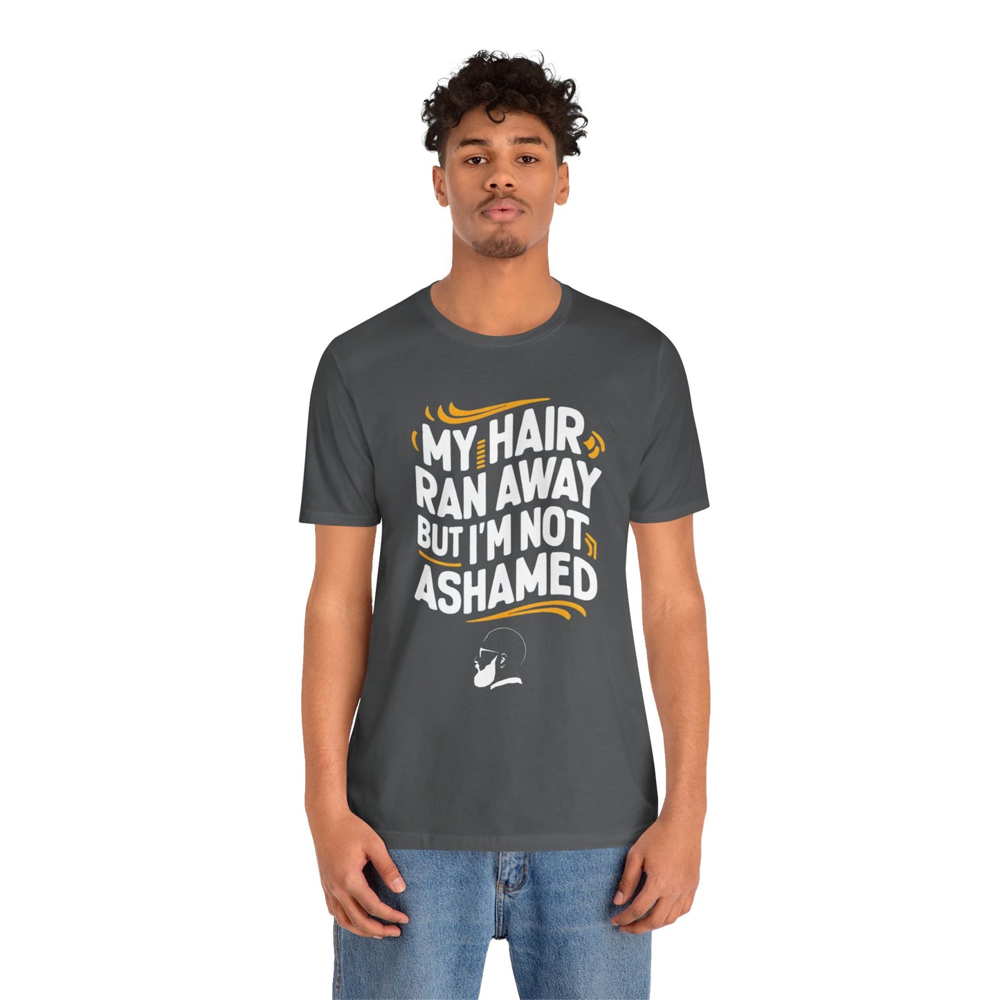 A  t-shirt with the text "My Hair Ran Away But I'm Not Ashamed" in bold white and yellow letters, accompanied by a playful illustration of a bald head with a smile.