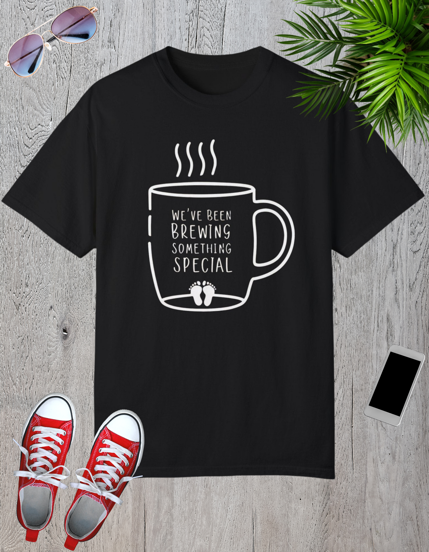 Black t-shirt featuring a coffee mug graphic with the text "We've Been Brewing Something Special" and tiny baby footprints.