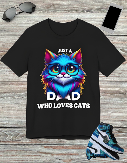 T-shirt featuring a vibrant and colorful graphic of a cat wearing glasses, with the text "Just a Dad Who Loves Cats" prominently displayed. Perfect for cat dads and Father's Day gifts.