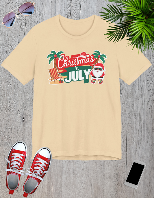 Tropical-themed t-shirts featuring the text "Christmas in July" with festive elements like palm trees, beach chairs, and a Santa.