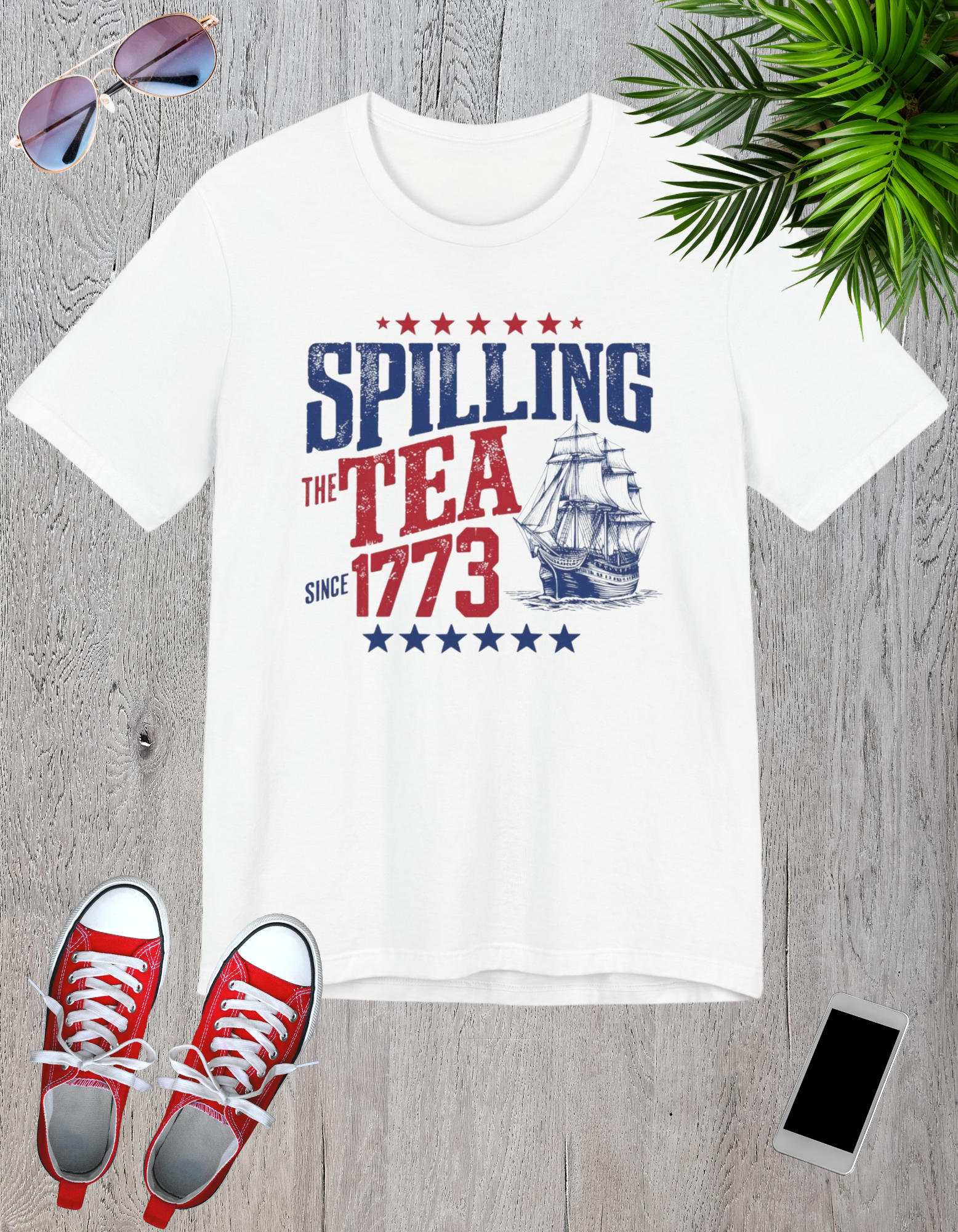 Various t-shirts featuring the text "Spilling the Tea Since 1773" with vintage-inspired graphics of ships and patriotic elements.