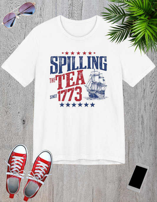 Various t-shirts featuring the text "Spilling the Tea Since 1773" with vintage-inspired graphics of ships and patriotic elements.