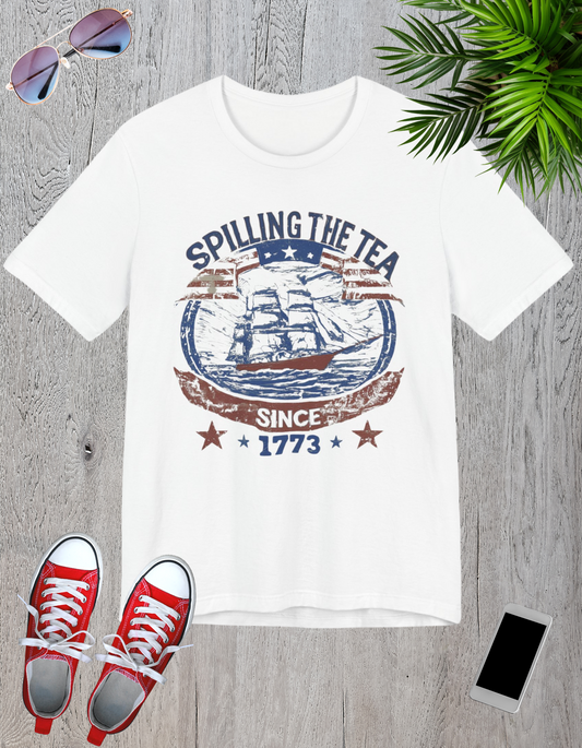 Various t-shirts featuring the text "Spilling the Tea Since 1773" with vintage-inspired graphics of ships and patriotic elements.