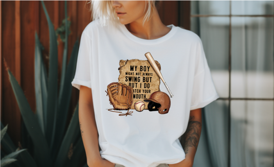 A t-shirt with a vintage-style baseball graphic featuring a baseball bat, glove, and helmet.  The text "My Boy Might Not Always Swing But I Do So Watch Your Mouth" is written in white above the graphic.